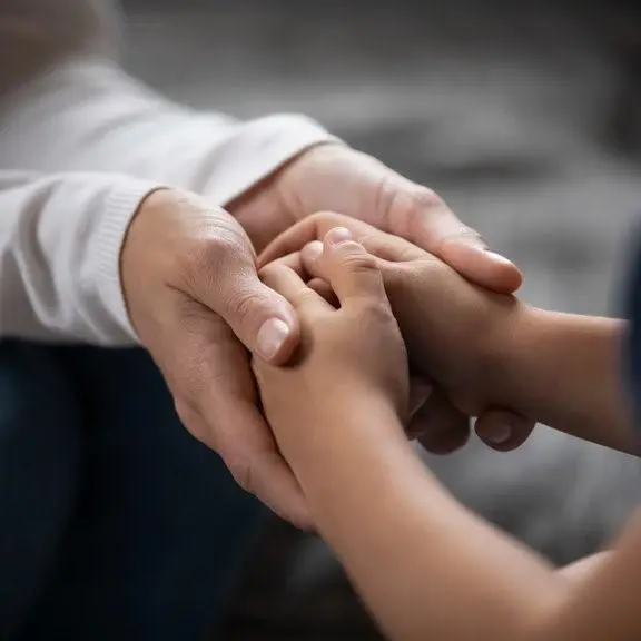 Foster parent holding a child's hands in support