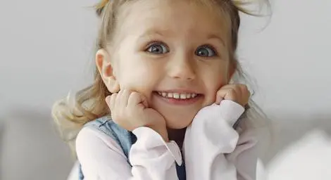little-girl-with-pig-tails-smiling-at-the-camera-there-is-a-toy-zebra-on-the-table-in-front-of-her